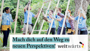 Auf dem Bild bauen Menschen in einer Gruppe gemeinsam ein Haus im Freiwilligendienst.