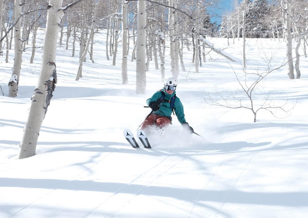 Foto: junger Mann fährt auf Skiern einen schneebedeckten Abhang hinunter